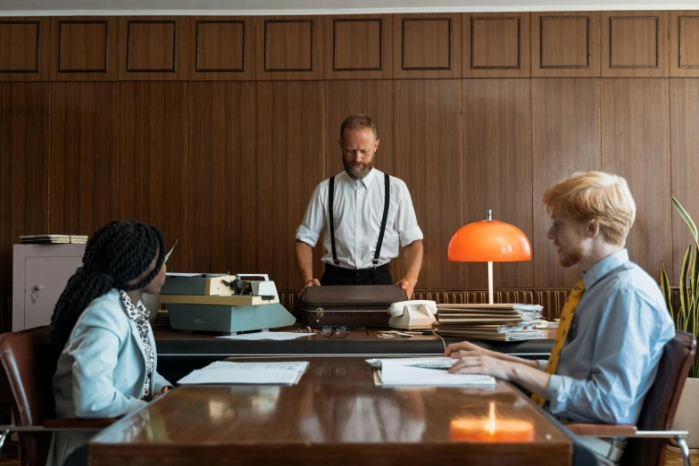 a group of people sitting around a wooden table, by Dietmar Damerau, pexels contest winner, private press, moody : : wes anderson, in office, midcentury modern, set inside of the bank