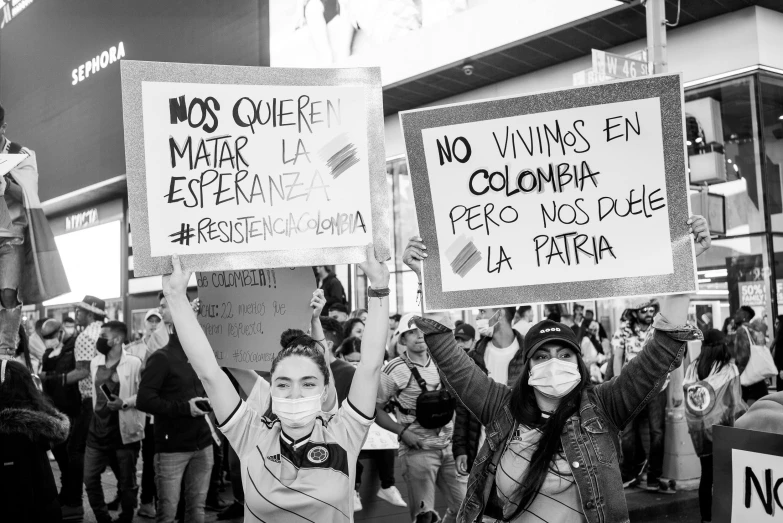 a group of people walking down a street holding signs, a black and white photo, by Gina Pellón, neoism, colombia, 2 0 2 2 photo, protesters holding placards, --n 6