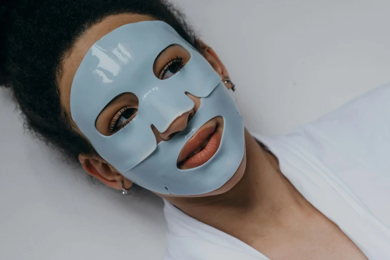 a woman with a blue mask on her face, trending on pexels, glossy white, with grey skin, pokimane, light blue