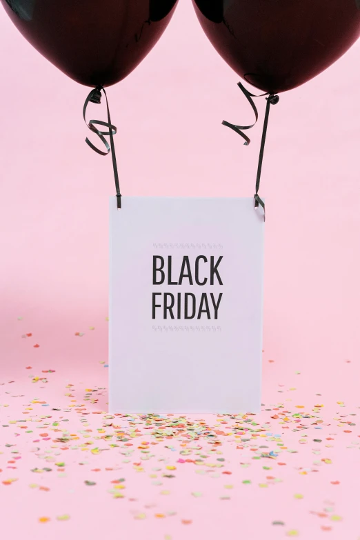 two red balloons and a black friday sign with confetti sprinkles on a pink background, a black and white photo, by Julia Pishtar, happening, matte print, back, black robe, bl