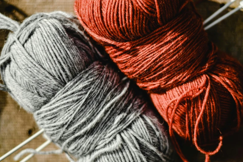 a couple of balls of yarn sitting on top of a table, trending on pexels, arts and crafts movement, red brown and grey color scheme, thumbnail, grey, textile