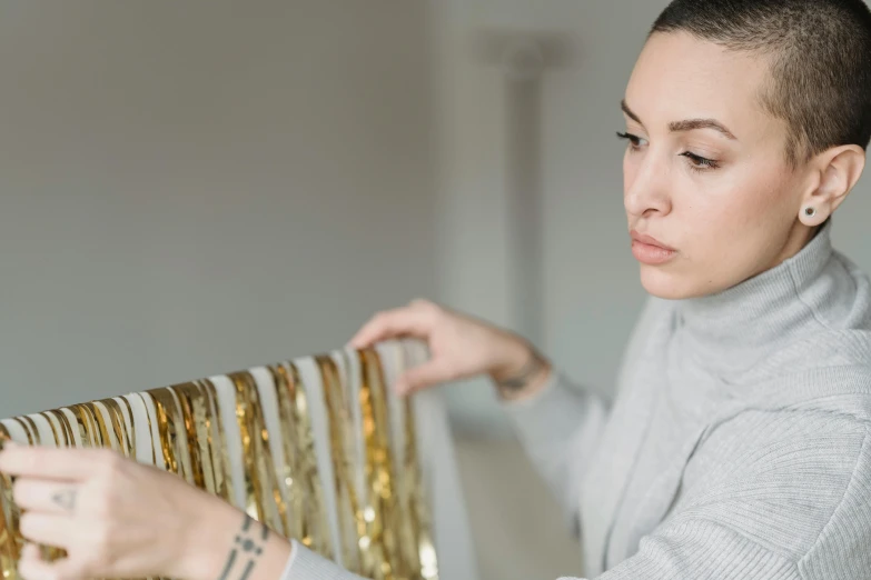 a woman sitting on top of a couch next to a radiator, trending on pexels, process art, golden ribbons, holding gold, shiny materials, profile image