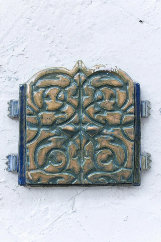 a close up of a tile on a wall, an album cover, inspired by Luis Paret y Alcazar, unsplash, arabesque, blue door, ornamental armor, wood carving, taken in the mid 2000s