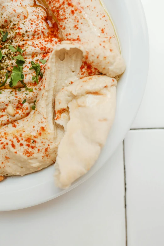 a white plate topped with hummus and pita bread, by Will Ellis, trending on unsplash, dau-al-set, low detail, dolman, panoramic shot, kailee mandel