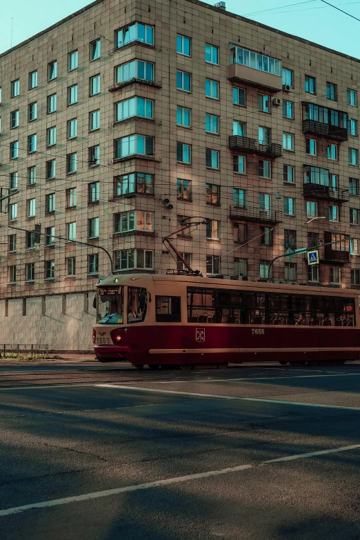a red bus driving down a street next to a tall building, unsplash contest winner, socialist realism, brown and cyan color scheme, фото девушка курит, square, tram