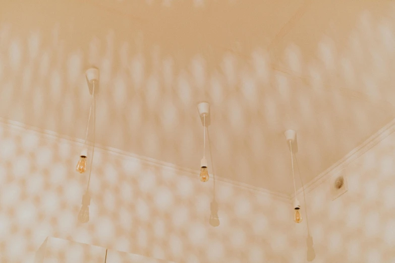 a group of light bulbs hanging from the ceiling, an ambient occlusion render, trending on unsplash, light and space, orange and white color scheme, sand - colored walls, tiny points of light, light academia aesthetic