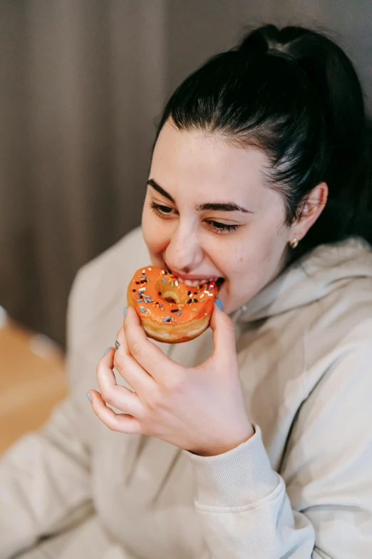 a woman sitting at a table eating a doughnut, trending on pexels, mouth slightly open, 18 years old, orange fluffy belly, manuka