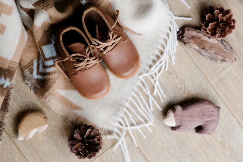 a pair of baby shoes sitting on top of a blanket, by Romain brook, trending on pexels, wears brown boots, wood accents, festive, caramel