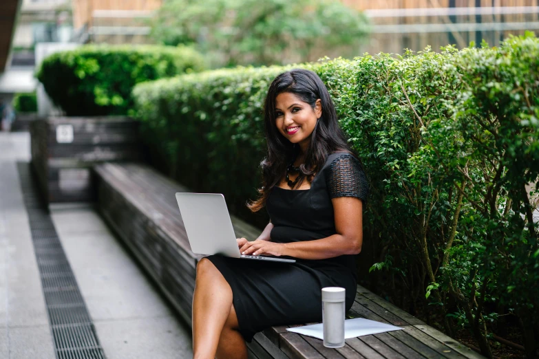 a woman sitting on a bench with a laptop, a portrait, pexels contest winner, wearing a formal dress, school curriculum expert, freida pinto, working