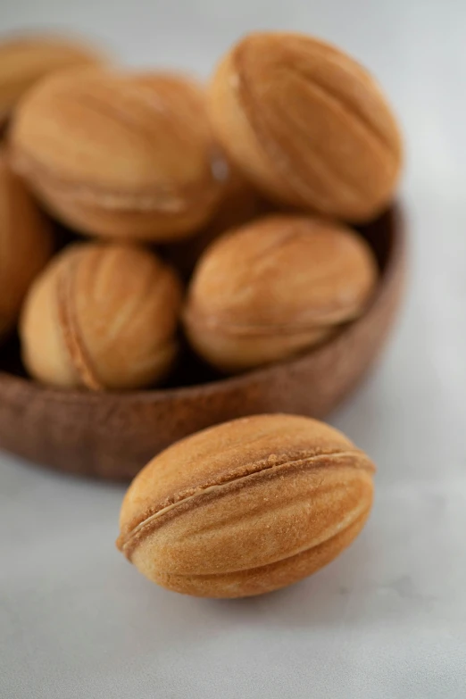 a wooden bowl filled with almonds on top of a table, inspired by Károly Patkó, hurufiyya, macaron, corduroy, dynamic closeup, small in size