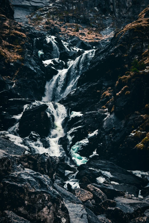 a waterfall in the middle of a rocky area, pexels contest winner, telephoto shot, highlands, twisted waterway, album cover