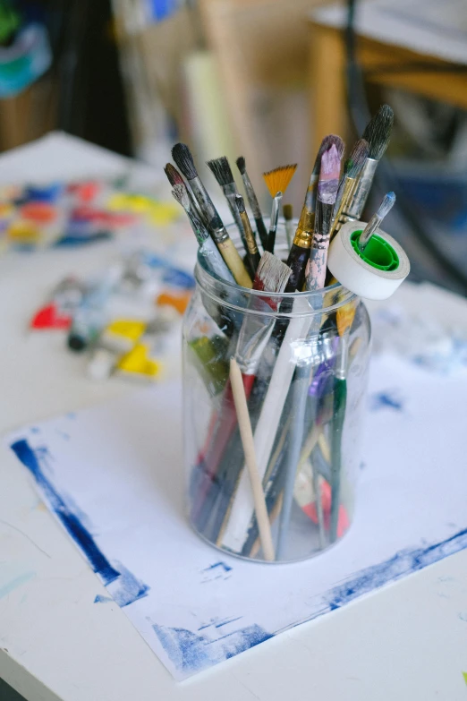 a jar of paint brushes sitting on top of a table, a photorealistic painting, inspired by artist, pexels, academic art, inside a cluttered art studio, digital paintin, ilustration, mate painting