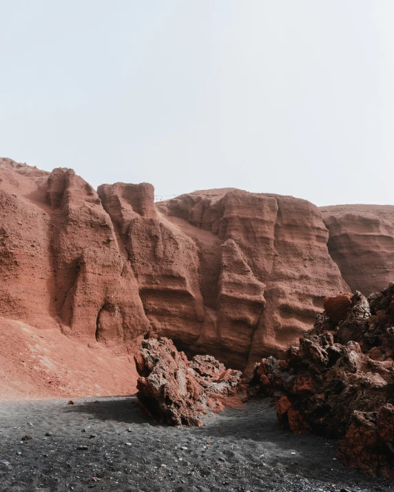 a man riding a motorcycle down a dirt road, an album cover, by Alexis Grimou, pexels contest winner, les nabis, red sandstone natural sculptures, found on a volcano, beach is between the two valleys, imbalanced mars. rugged