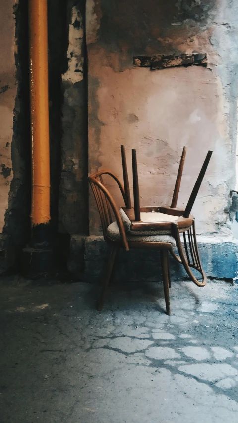 a chair that is sitting in front of a window, inspired by Balthus, unsplash contest winner, in an alley, ffffound, thrown tables, in a pub