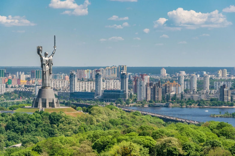 a large statue sitting on top of a lush green hillside, pexels contest winner, socialist realism, neo kyiv, skyline showing, 🚿🗝📝, panoramic