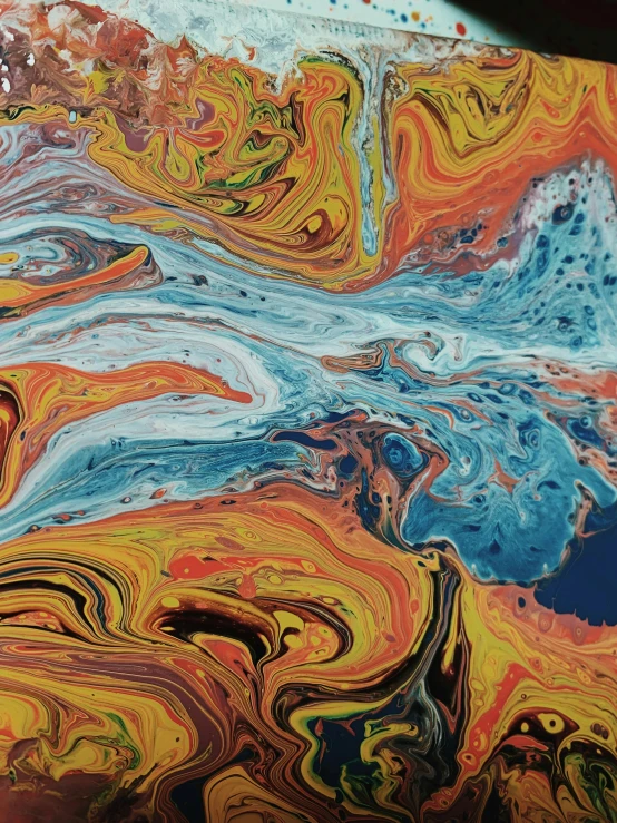 a close up of a piece of art on a table, inspired by Umberto Boccioni, trending on unsplash, oil spills, flowing milk, some orange and blue, album cover