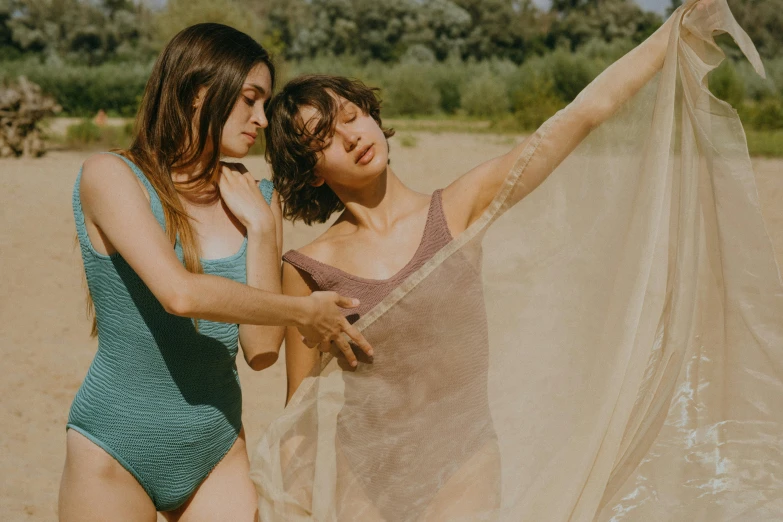 a couple of women standing next to each other on a beach, by Attila Meszlenyi, trending on pexels, renaissance, diaphanous translucent cloth, brunette, float, lined in cotton