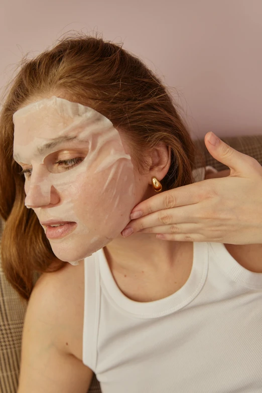 a woman sitting on a couch with a sheet on her face, by Julia Pishtar, trending on pexels, renaissance, glass facial muscles, gold mask, small chin, wearing a patch over one eye