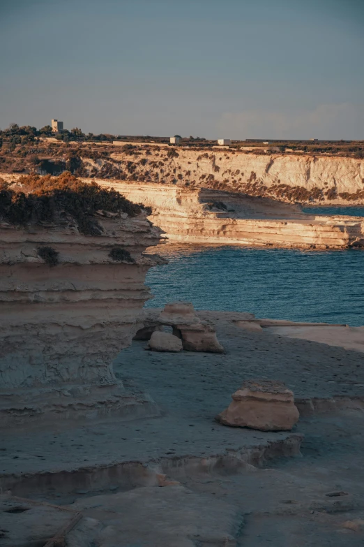 a large body of water sitting on top of a sandy beach, by Alexis Grimou, les nabis, apulia, cliff side at dusk, low quality photo, rock quarry location