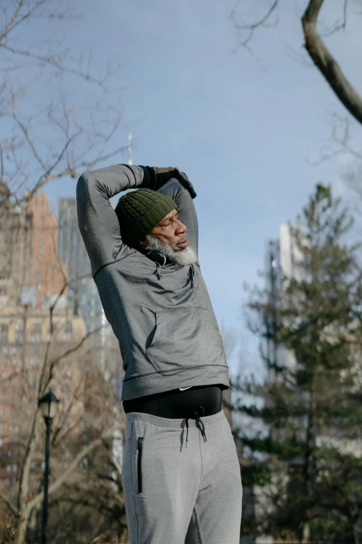 a man standing on a skateboard in a park, unsplash, happening, he also wears a grey beanie, arms raised, morgan freeman, in new york city