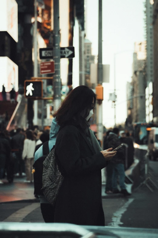 a woman standing on a city street looking at her phone, pexels contest winner, happening, time square, low quality photo, wearing jeans and a black hoodie, busy people