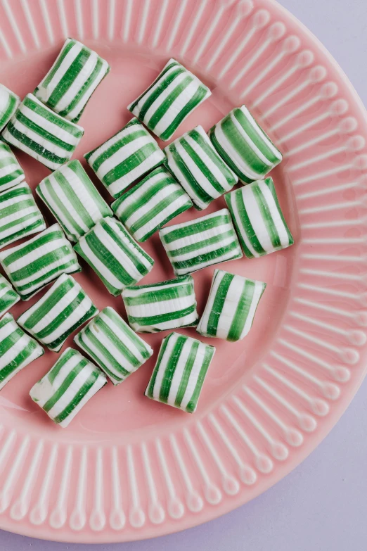 a pink plate topped with green and white striped candy, emily rajtkowski, stacks, deep green, swedish