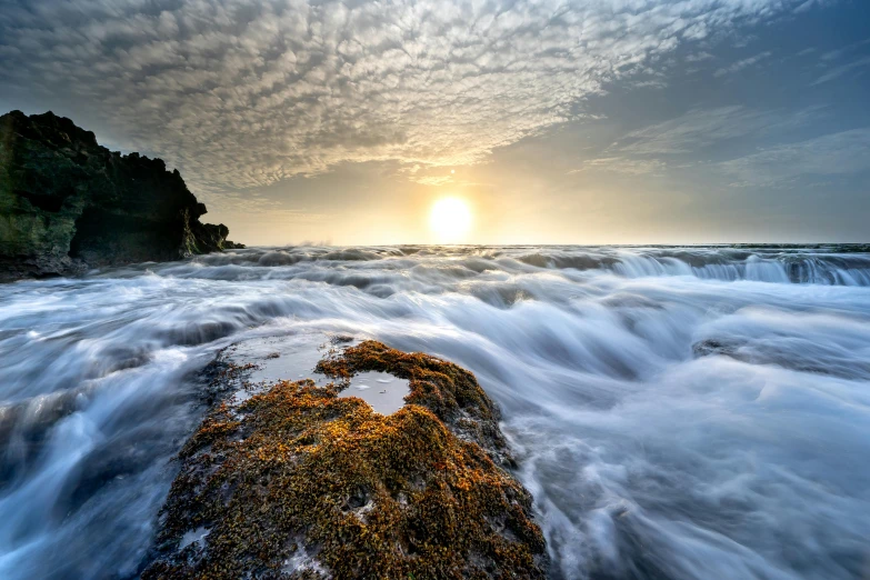 a large body of water next to a rocky shore, by Basuki Abdullah, unsplash contest winner, romanticism, winter sun, sea spray, today\'s featured photograph 4k, rushing water