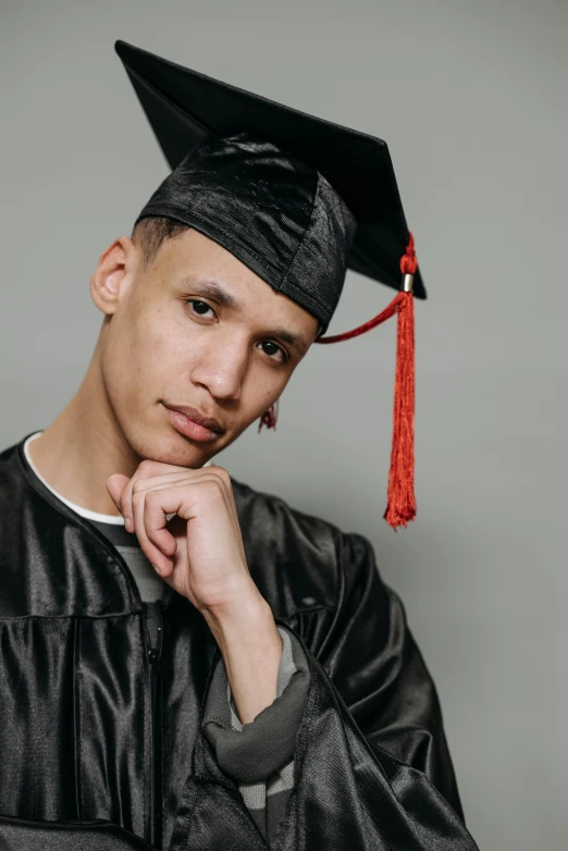 a man wearing a graduation cap and gown, a colorized photo, trending on pexels, mix of ethnicities and genders, non binary model, young man with short, studio portrait