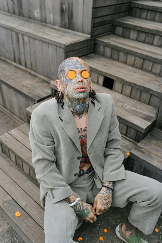 a man with tattoos on his face sitting on steps, inspired by James Bolivar Manson, trending on pexels, wearing a worn out suit, wearing orange sunglasses, yung lean, reptilian cyborg