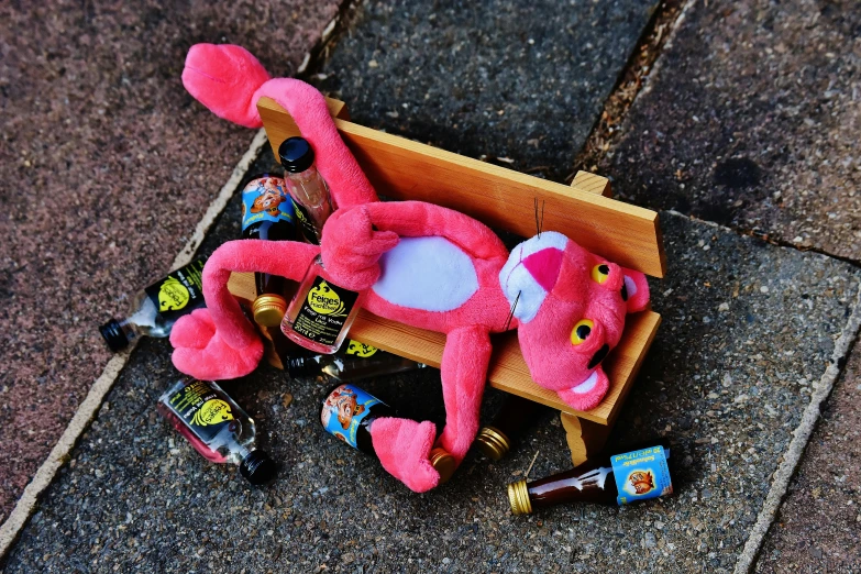 a pink stuffed animal laying on top of a wooden box, a picture, by Niko Henrichon, booze, broken toys, garfield, ooak