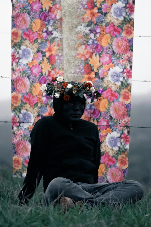 a man sitting in the grass with a flower crown on his head, an album cover, inspired by Dan Hillier, pexels contest winner, black face, chile, featured in pictoplasma, made of fabric