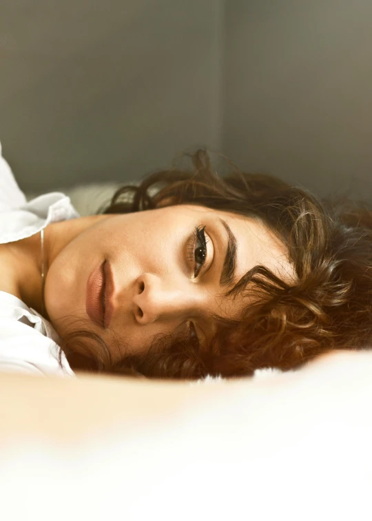 a close up of a person laying on a bed, a portrait, inspired by Elsa Bleda, trending on pexels, renaissance, brown curly hair, thoughtful expression, beautiful iranian woman, unhappy