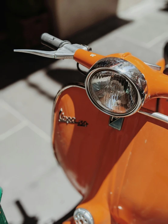 an orange motor scooter parked on a sidewalk, pexels contest winner, round headlights, up close image, vintage photo, 🚿🗝📝