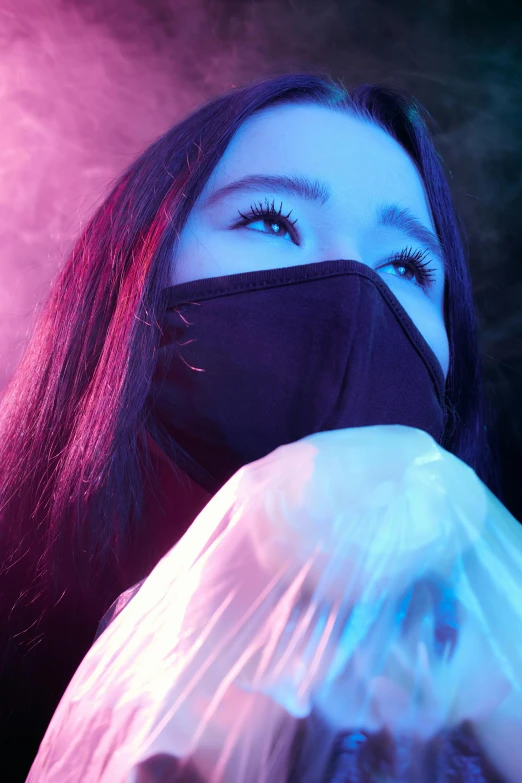 a woman wearing a face mask and holding a plastic bag, an album cover, trending on pexels, glowing with colored light, jingna zhang, irelia, scene from a rave