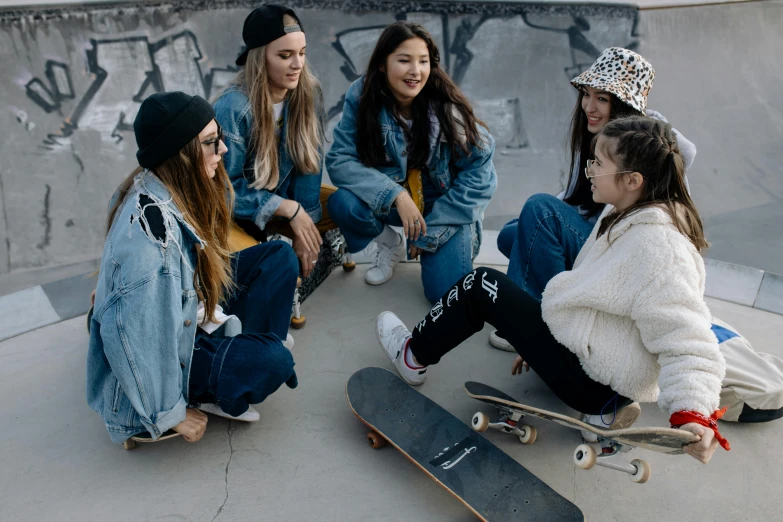 a group of girls sitting on the ground with skateboards, trending on pexels, profile image, beanie, wearing double denim, group sit at table