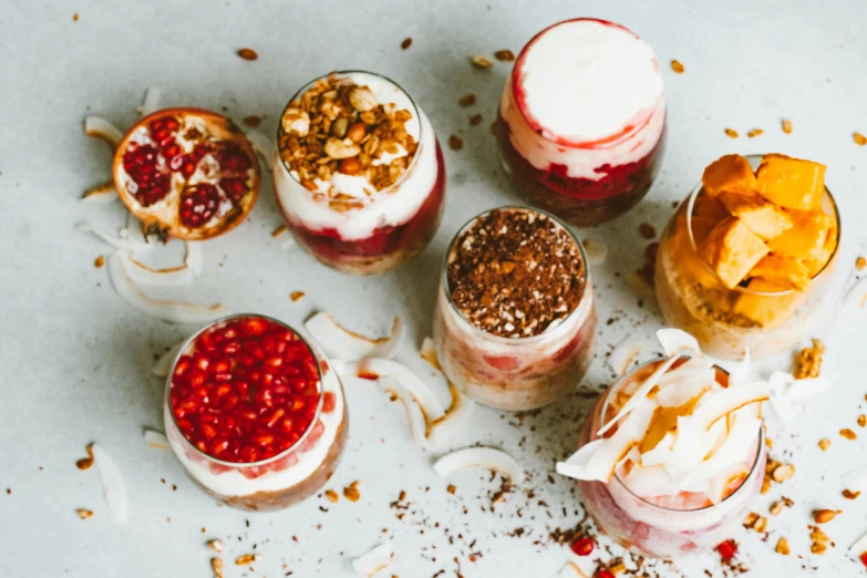 a group of desserts sitting on top of a table, by Emma Andijewska, trending on pexels, jars, coconuts, yogurt, red brown and white color scheme