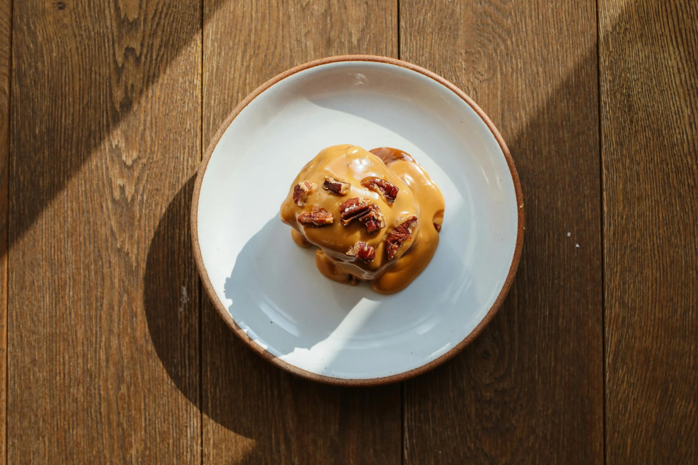 a white plate topped with food on top of a wooden table, inspired by Richmond Barthé, unsplash, caramel, bun ), seasonal, view from below