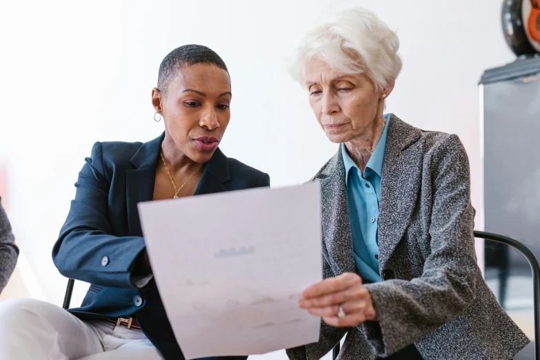 two women sitting at a table looking at a piece of paper, pexels contest winner, elderly, professional image, thumbnail, inspect in inventory image