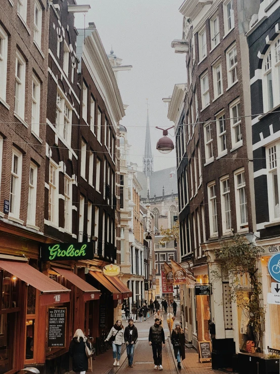 a group of people walking down a street next to tall buildings, a photo, by Jan Tengnagel, pexels contest winner, happening, view of houses in amsterdam, 🎀 🍓 🧚, colonial era street, brown