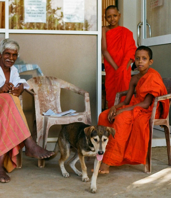 a group of people sitting on a porch with a dog, pexels contest winner, hurufiyya, sri lanka, 2 1 st century monk, an old lady with red skin, 15081959 21121991 01012000 4k