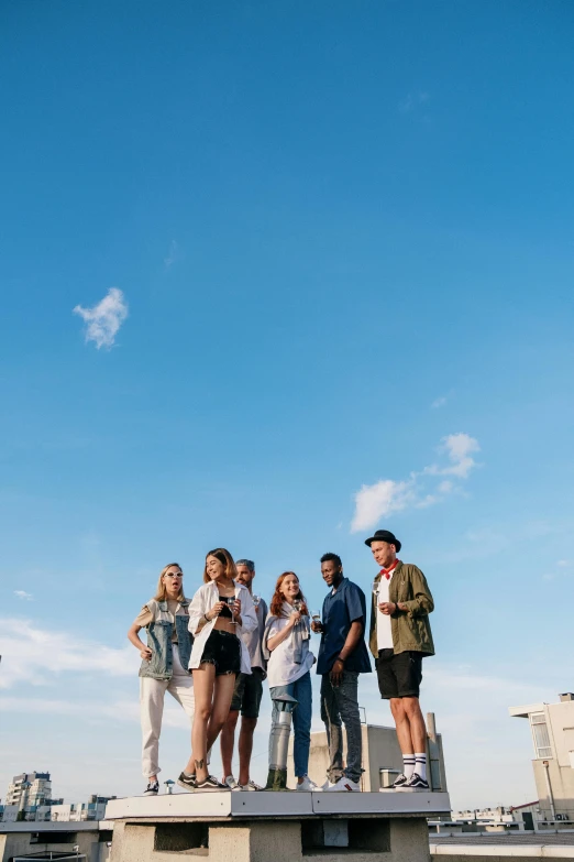 a group of people standing on top of a building, trending on pexels, blue skies, medium shot portrait, summer setting, cast