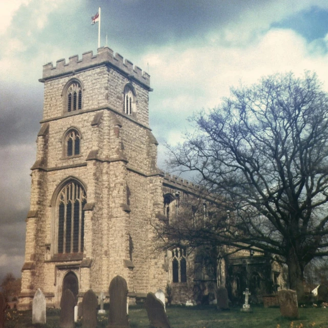 a tall tower with a flag on top of it, an album cover, by Kev Walker, flickr, renaissance, churchyard, taken on a 1970s polaroid camera, barnet, scene from church