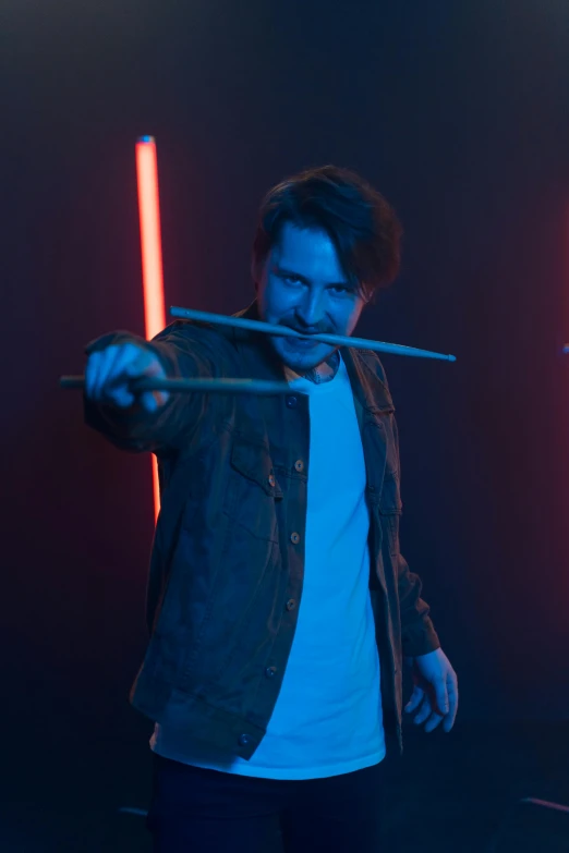 a man standing in a dark room holding a pair of scissors, inspired by John Carpenter, trending on reddit, playing drums, xqc, with lightsaber sword, sneering. cinematic lighting