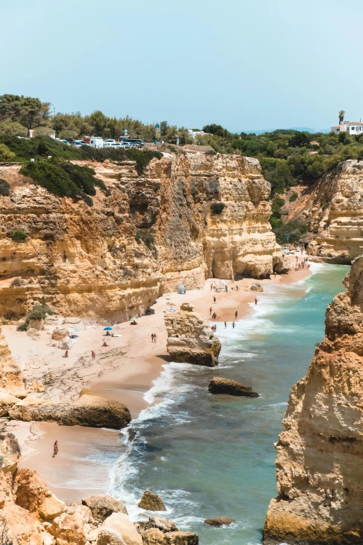 a group of people standing on top of a sandy beach, coastal cliffs, pools of water, rocha, limestone