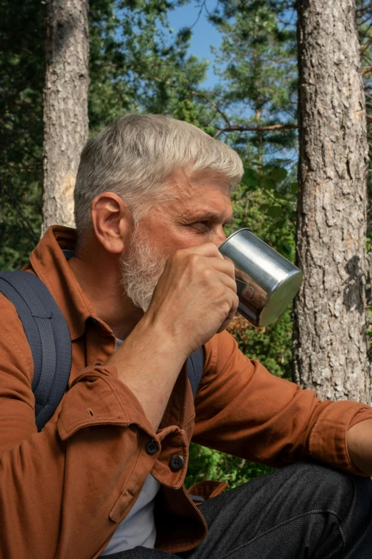 a man sitting in the woods drinking from a cup, silver hair and beard, coffee smell, geology, profile image