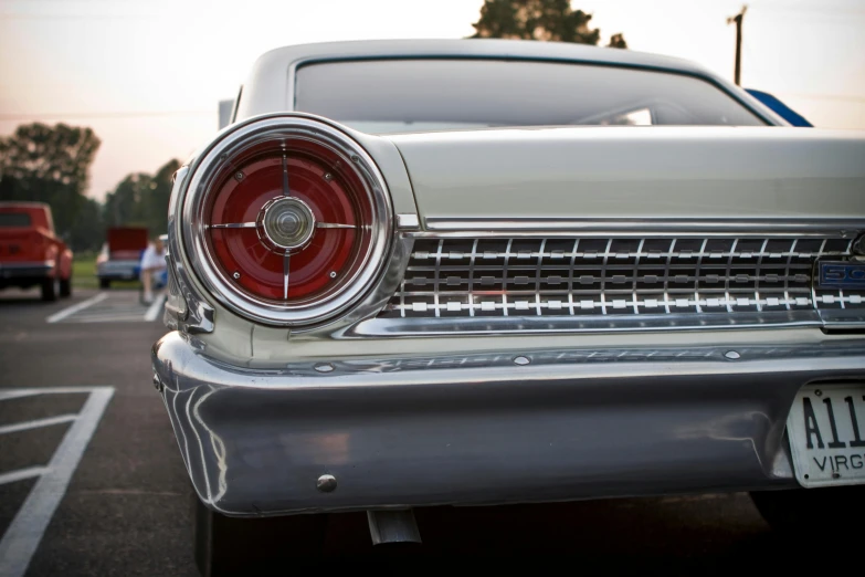 a classic car is parked in a parking lot, by David Donaldson, pexels contest winner, photorealism, tail lights, ford, white metallic, 1960s color photograph