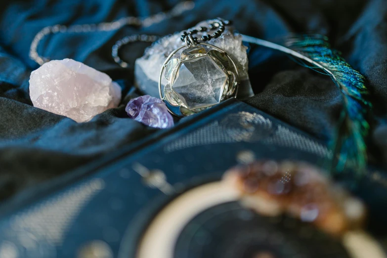 a couple of necklaces sitting on top of a blue cloth, a still life, trending on pexels, amethyst mineral quartz, with black magic powers, album, clear focused details