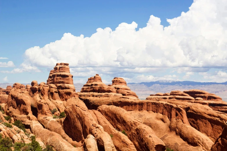 a large rock formation in the middle of a desert, pexels contest winner, puffy clouds in background, arches, background image, moab