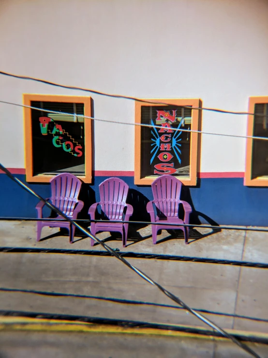 a couple of purple chairs sitting in front of a building, by Ben Thompson, photorealism, tacos, refracted color lines, found on google street view, 1999 photograph