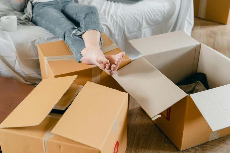 a woman laying on the floor next to a pile of boxes, by Carey Morris, pexels contest winner, hurufiyya, delivering parsel box, melbourne, seams, youtube thumbnail